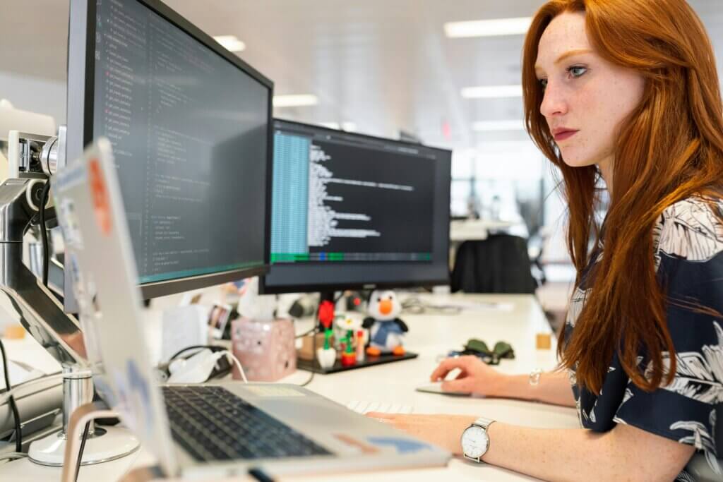 Mujer programadora trabajando en dos monitores.