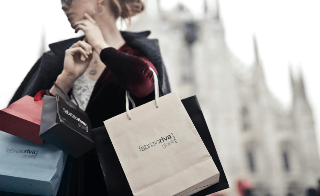 Mujer de compras con bolsas de marca en un entorno urbano.