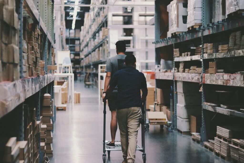 Trabajadores moviendo productos en un almacén grande.