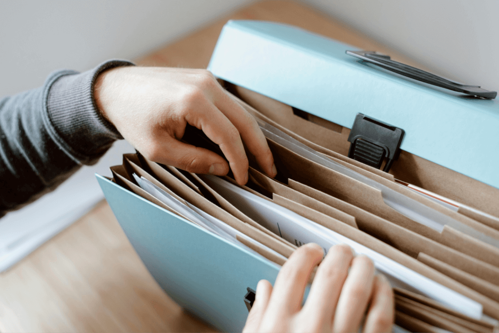 Mano organizando documentos en un archivador de oficina.