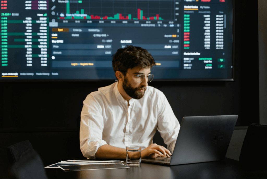 Hombre analizando datos financieros en laptop con gráficos.